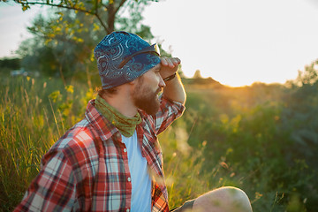 Image showing Young caucasian man with backpack sitting on the top of hill