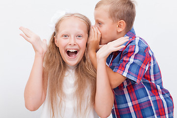 Image showing Teenage boy whispering in the ear a secret to teen girl on white  background