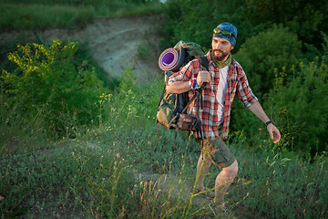 Image showing Young caucasian man with backpack walking on the top of hill