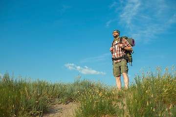 Image showing Young caucasian man with backpack standing on the top of hill
