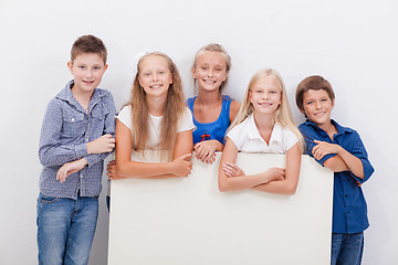 Image showing Happy smiling group of kids, boys and girls, showing board 