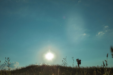 Image showing Young caucasian man with backpack walking on a green meadow