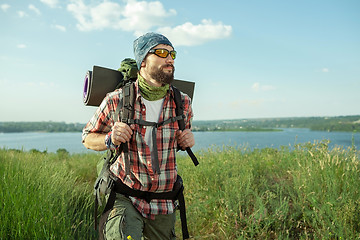 Image showing Young caucasian man with backpack walking on the top of hill