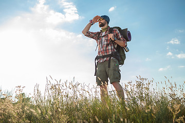 Image showing Young caucasian man with backpack standing on the top of hill