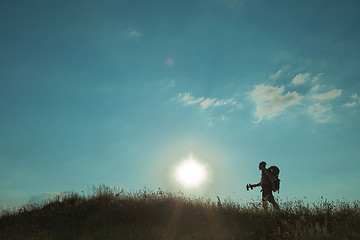 Image showing Young caucasian man with backpack walking on a green meadow