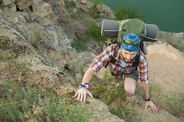 Image showing Young caucasian man with backpack climbing the rock