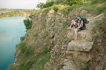 Image showing Young caucasian man with backpack sitting on the top of hill