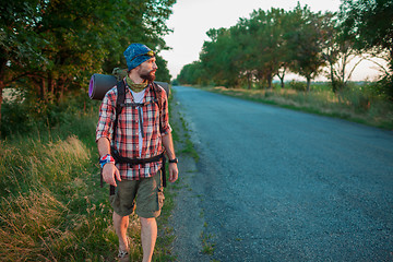 Image showing Young caucasian tourist hitchhiking along a road.