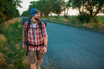 Image showing Young caucasian tourist hitchhiking along a road.