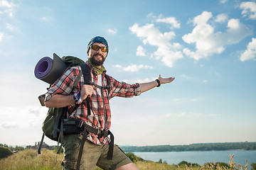 Image showing Young caucasian man with backpack standing on the top of hill