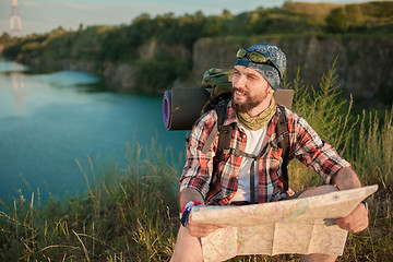 Image showing Young caucasian man with backpack sitting on the top of hill