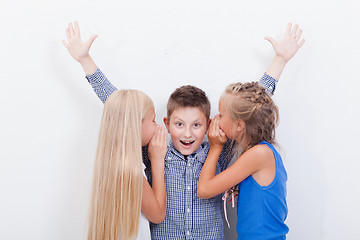 Image showing Teenage girsl whispering in the ears of a secret teen boy on white  background