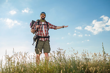 Image showing Young caucasian man with backpack standing on the top of hill