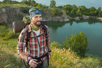 Image showing Young caucasian man with backpack walking on the top of hill