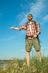 Image showing Young caucasian man with backpack standing on the top of hill