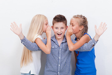 Image showing Teenage girsl whispering in the ears of a secret teen boy on white  background