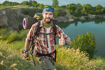 Image showing Young caucasian man with backpack walking on the top of hill