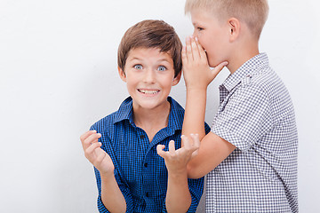 Image showing Teenage boy whispering in the ear a secret to friendl on white  background