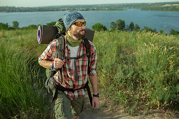 Image showing Young caucasian man with backpack walking on the top of hill