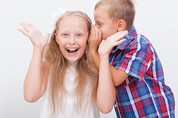 Image showing Teenage boy whispering in the ear a secret to teen girl on white  background