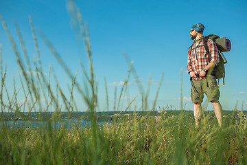 Image showing Young caucasian man with backpack standing on the top of hill