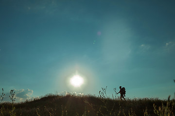 Image showing Young caucasian man with backpack walking on a green meadow