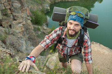 Image showing Young caucasian man with backpack rising on the rock