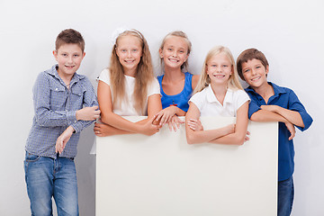 Image showing Happy smiling group of kids, boys and girls, showing board 