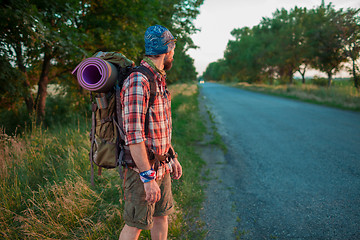 Image showing Young caucasian tourist hitchhiking along a road.