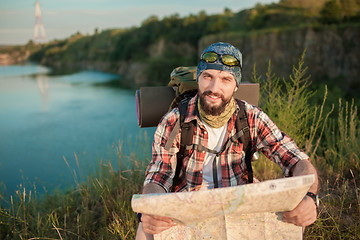 Image showing Young caucasian man with backpack sitting on the top of hill