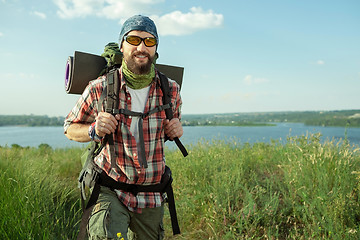 Image showing Young caucasian man with backpack walking on the top of hill