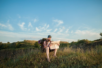 Image showing Young caucasian man with backpack sitting on the top of hill