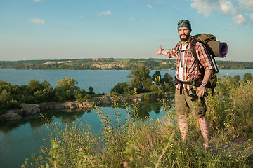 Image showing fully equipped tourist smiling on the background of lake