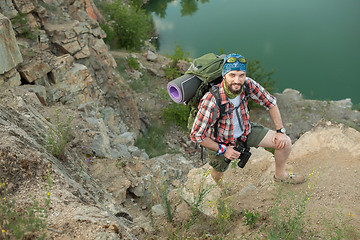 Image showing Young caucasian man with backpack climbing the rock