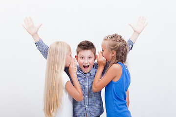 Image showing Teenage girsl whispering in the ears of a secret teen boy on white  background