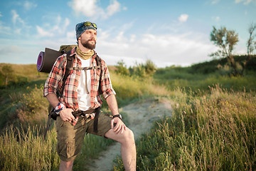 Image showing Young caucasian man with backpack walking on the top of hill