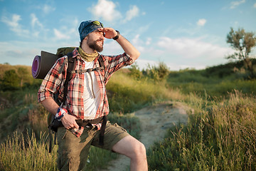 Image showing Young caucasian man with backpack walking on the top of hill