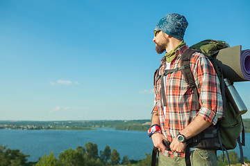 Image showing Young caucasian man with backpack standing on the top of hill