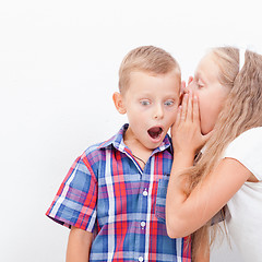 Image showing Teenage girl whispering in the ear of a secret teen boys on white  background