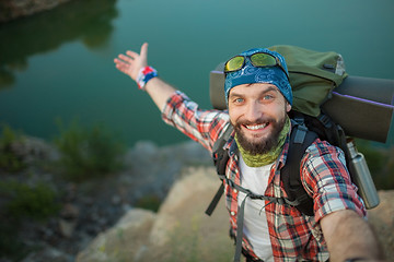 Image showing Young caucasian man with backpack standing on the top of hill