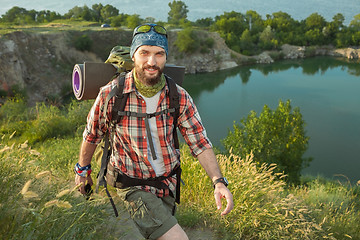 Image showing Young caucasian man with backpack walking on the top of hill