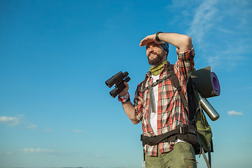 Image showing Young caucasian man with backpack standing on the top of hill