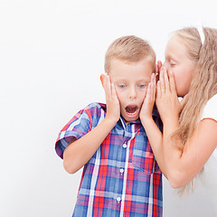 Image showing Teenage girl whispering in the ear of a secret teen boys on white  background