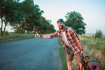 Image showing Young smilimg caucasian tourist on a road.