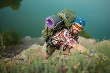 Image showing Young caucasian man with backpack climbing the rock