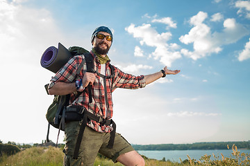 Image showing Young caucasian man with backpack standing on the top of hill