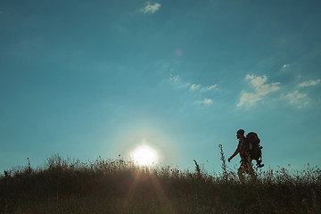 Image showing Young caucasian man with backpack walking on a green meadow