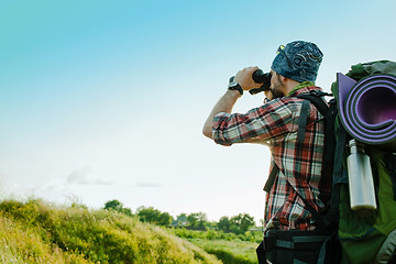 Image showing Young caucasian man with backpack standing on the top of hill