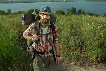 Image showing Young caucasian man with backpack walking on the top of hill