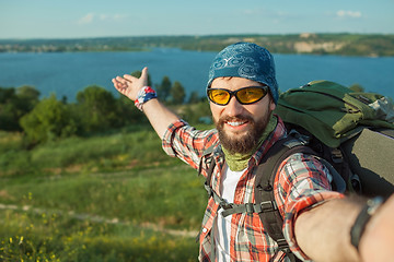 Image showing Young caucasian man with backpack standing on the top of hill